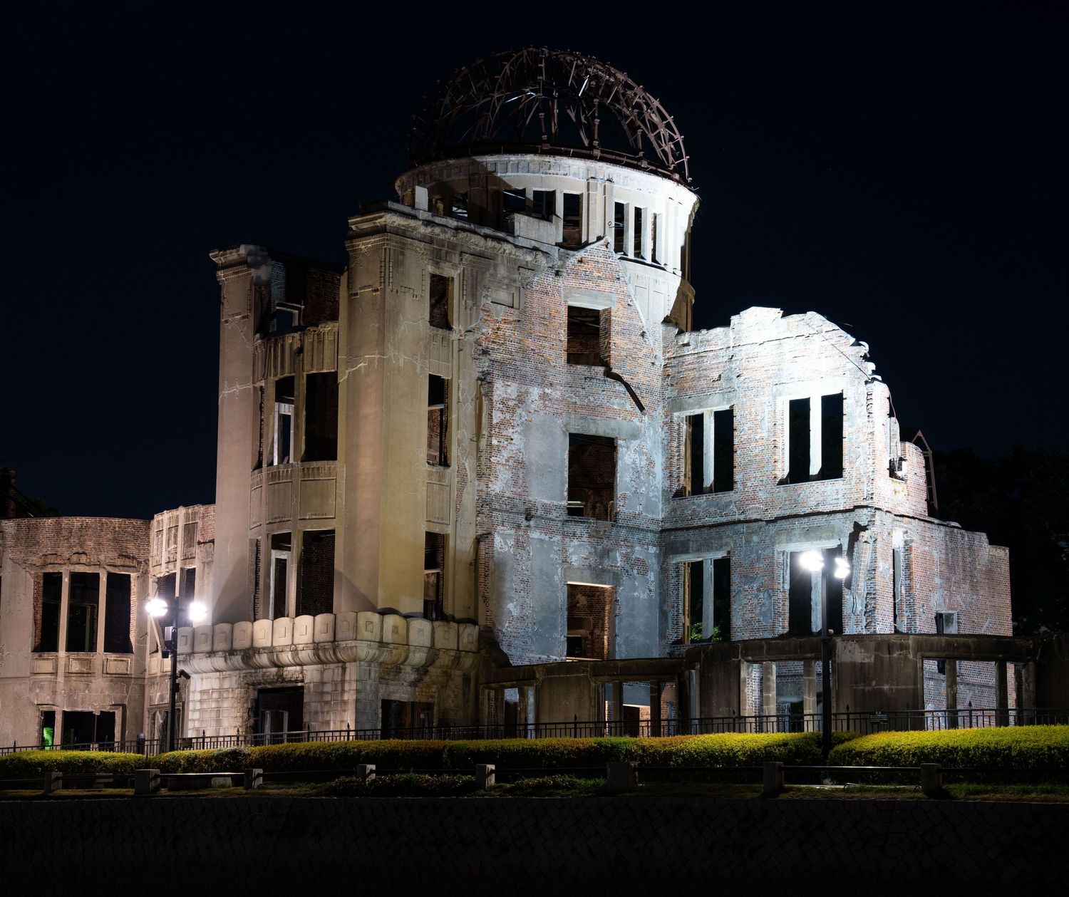 Panoramic night view of a historic damaged building illuminated by spotlights.