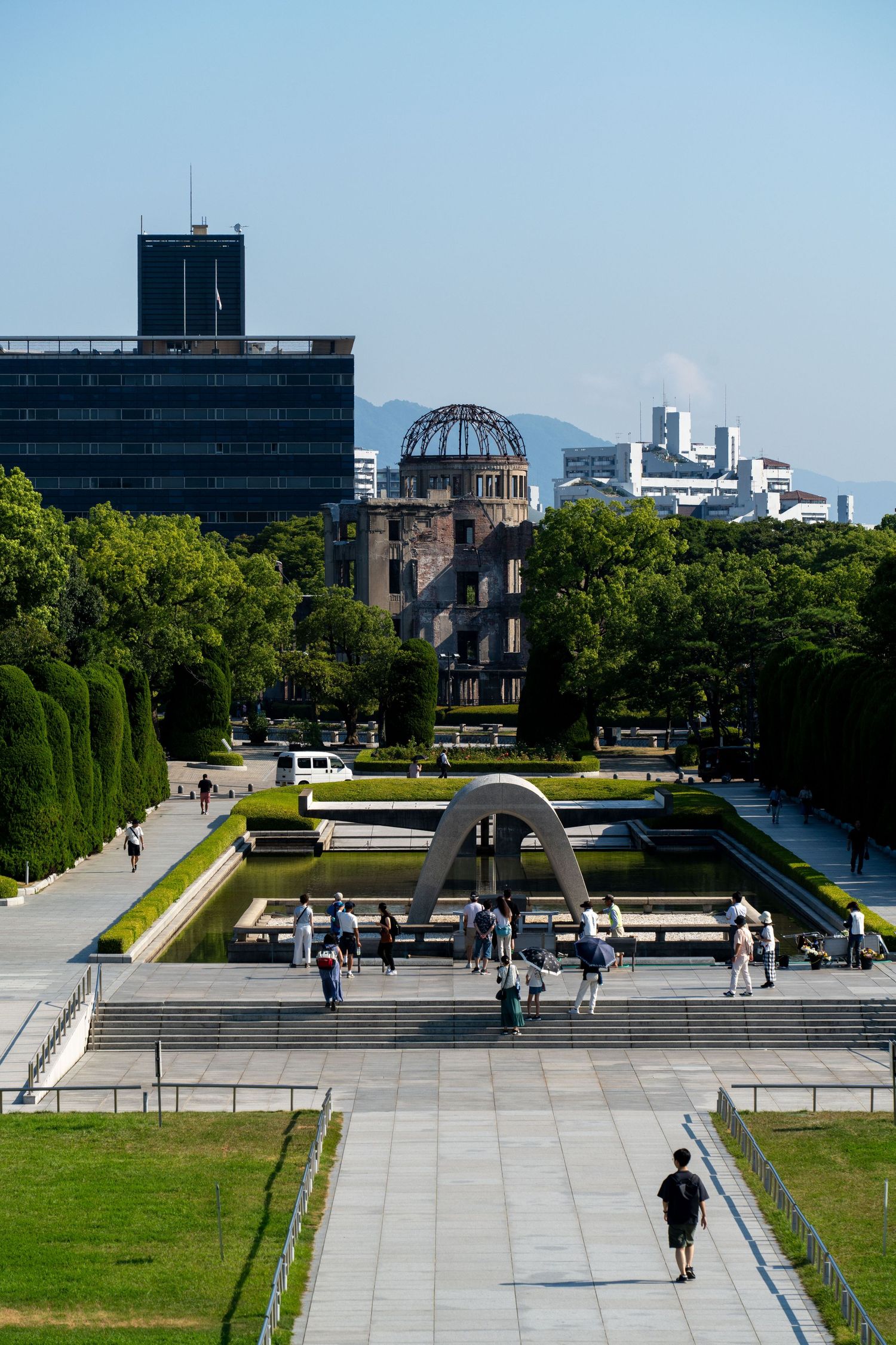 Wide plaza with modern buildings and steps leading to the Atomic Bomb Dome in Hiroshima Peace Memorial Park.