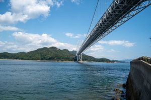 Scenic view of a large suspension bridge spanning across blue waters on a sunny day.