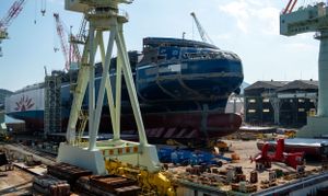 Industrial shipyard with large cranes and vessels under construction.