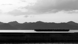 Black and white landscape of mountains and water with dramatic cloudy sky.
