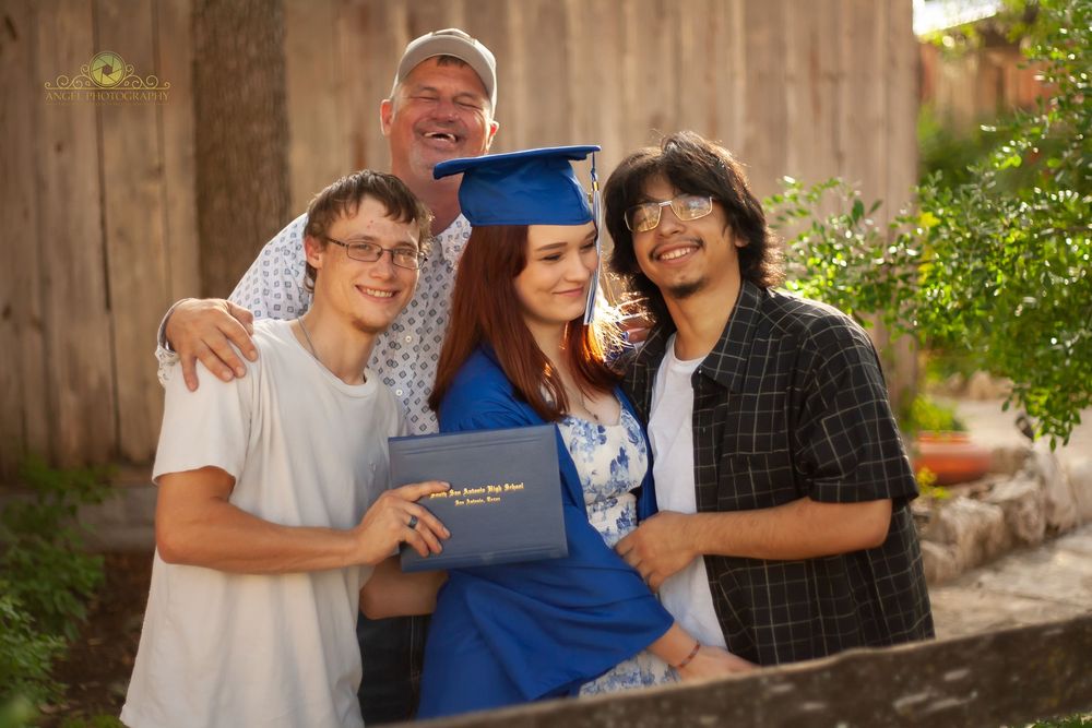A group of people sharing joyful moments and laughter together in an outdoor setting with a wooden fence backdrop.