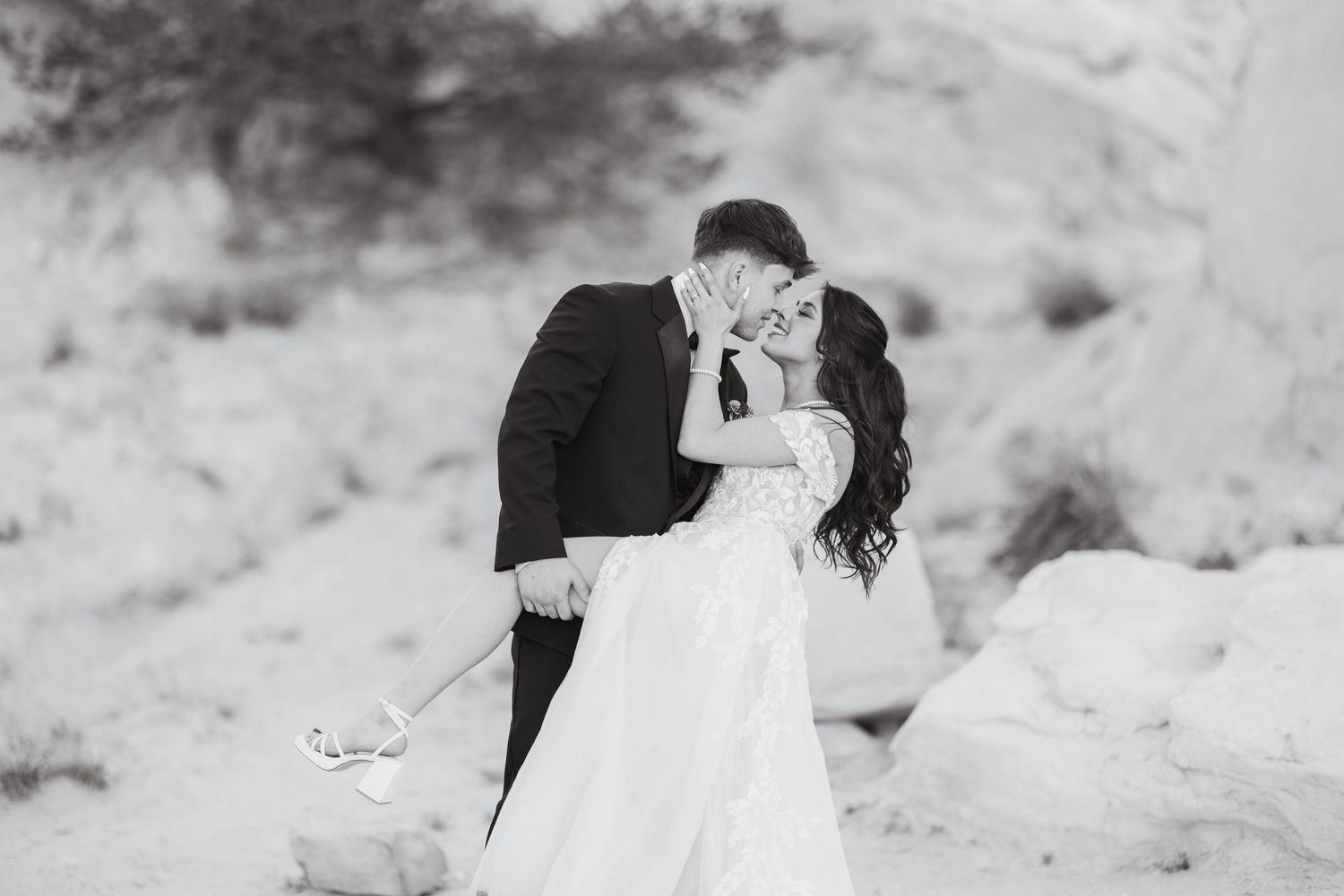 A romantic black and white wedding photo of a couple embracing against a snowy backdrop.