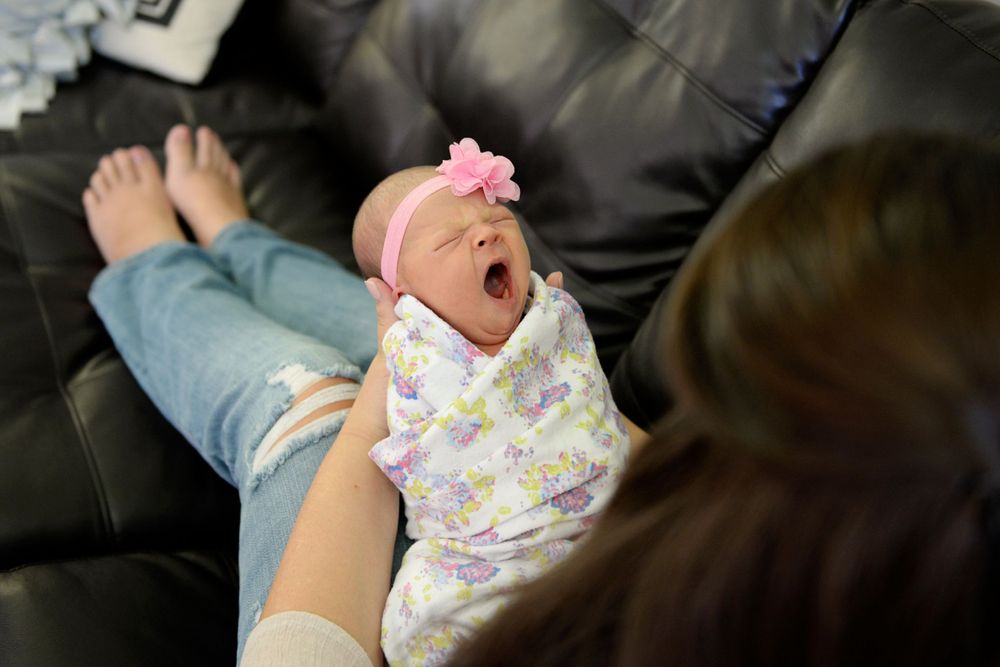 Infant wearing floral print outfit during candid lifestyle photography session.