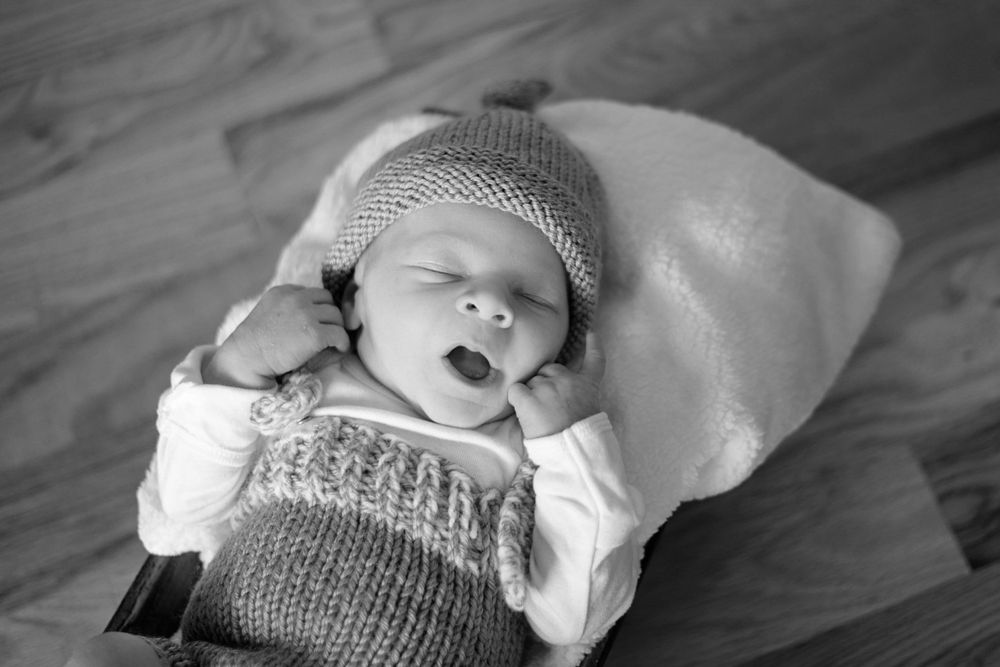 Black and white newborn photography featuring soft knit blanket and gentle natural lighting.