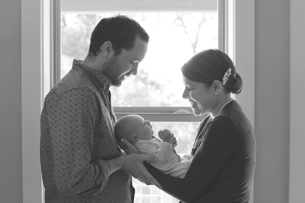 Natural light streams through window during intimate indoor portrait session.