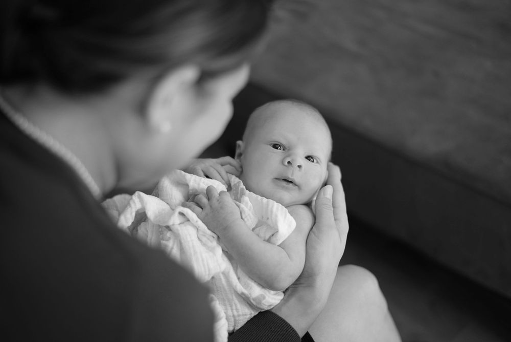 Black and white newborn photography with soft focus and gentle lighting effects.
