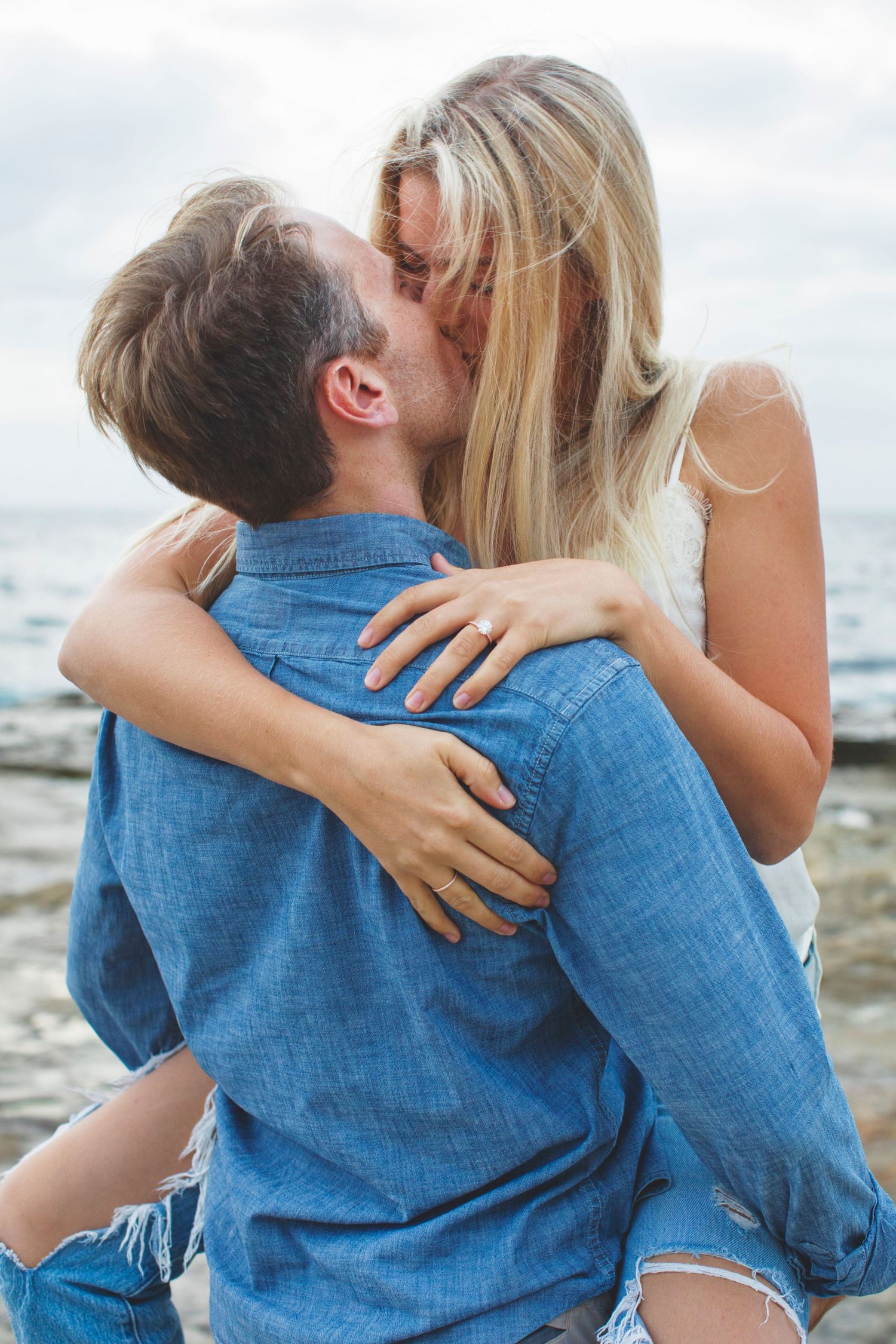Romantic embrace on rocky coastline during sunset.