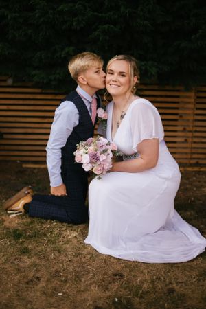 A sweet outdoor wedding moment captured in front of a wooden fence.