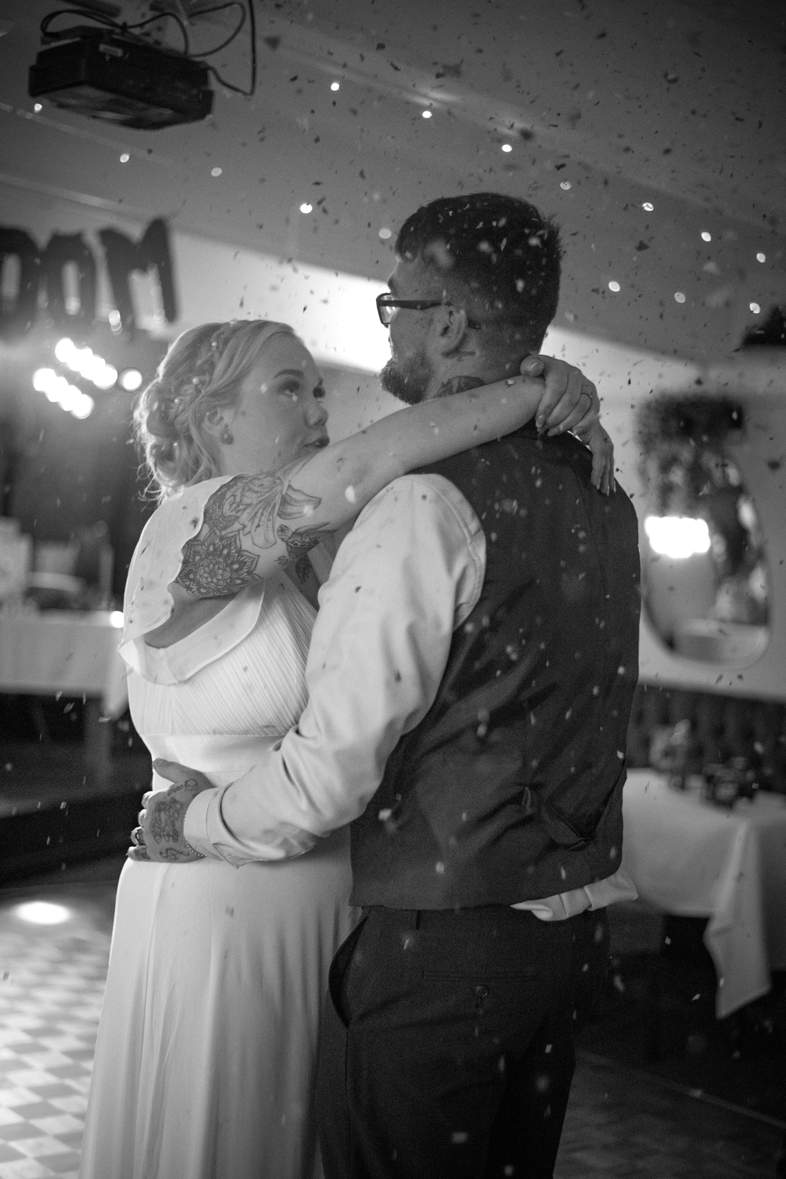 An intimate black and white photo of a couple dancing amid sparkles at their wedding reception.