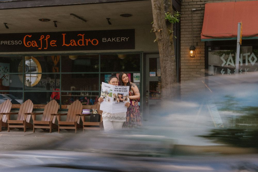 A couple sits on chairs outside Caffe Ladro bakery in a peaceful urban setting.