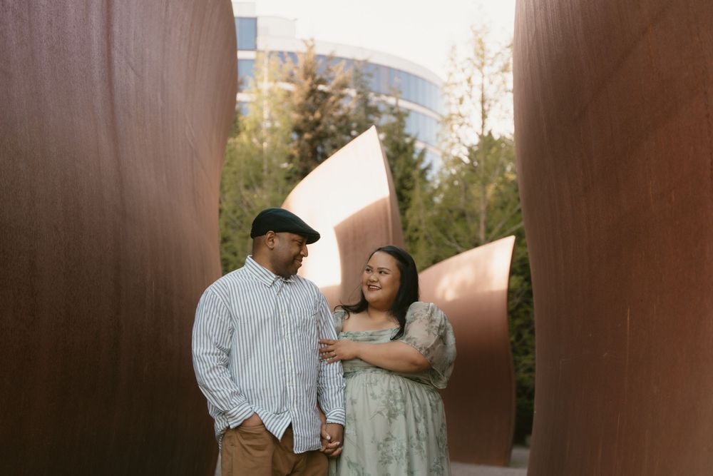 Couple sharing a tender moment between curved metal sculpture walls.