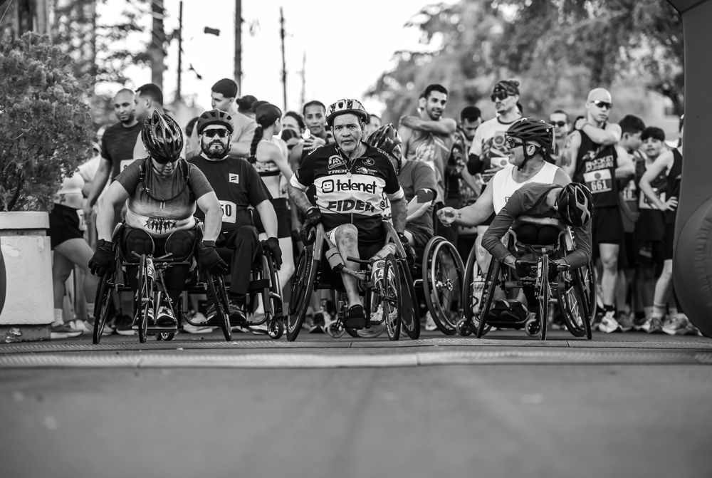 Black and white photograph of wheelchair athletes at start line of racing competition.