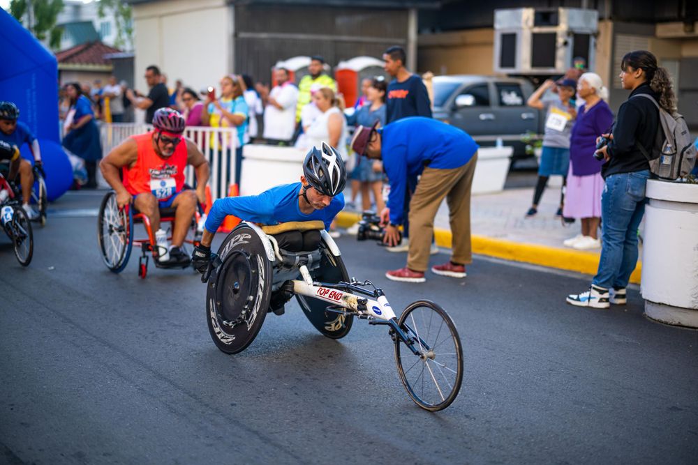 Paralympic athletes racing in wheelchairs on a competition track.