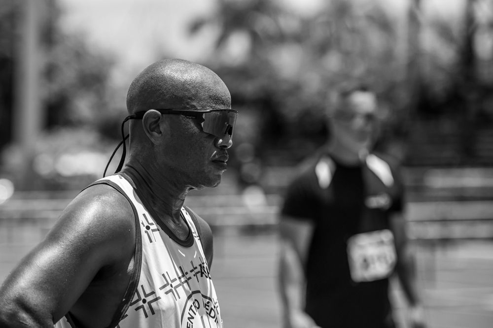 Athletes competing in a track and field event with hurdles on a sunny day.
