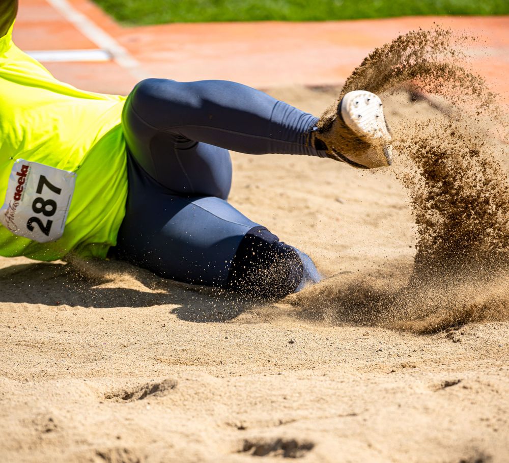 Close-up of sand flying during a long jump landing at a track meet.