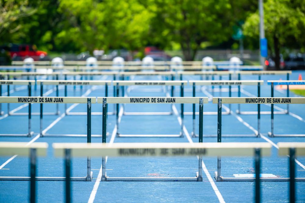 Row of blue track hurdles lined up on an outdoor athletic field.