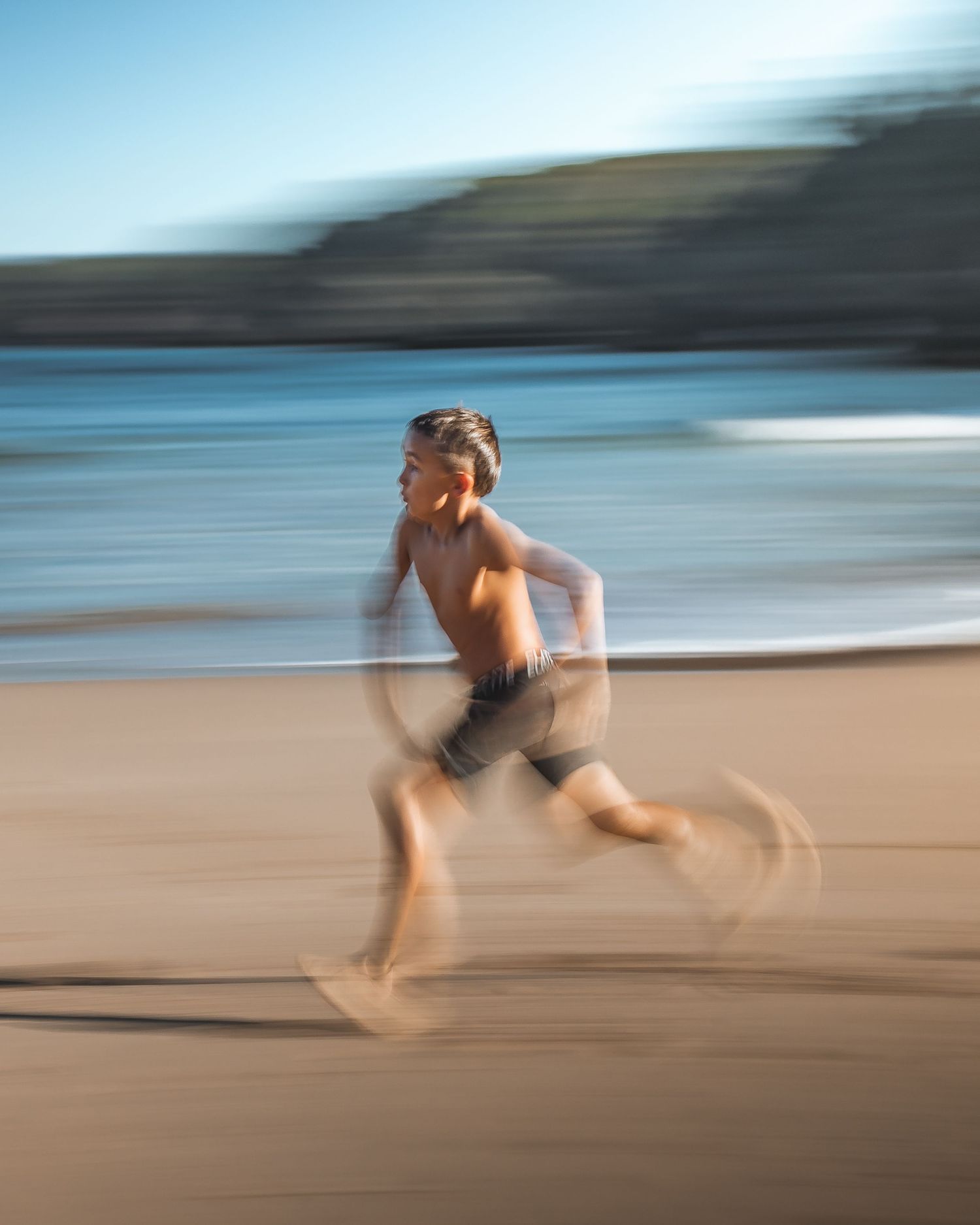 Motion blur photograph of a person running on a beach with ocean waves in background.