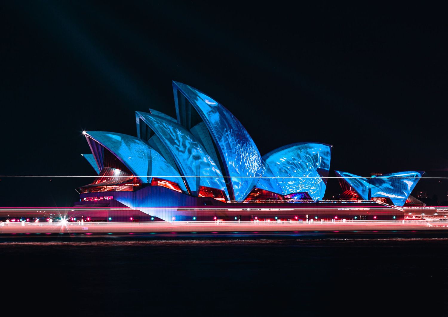 Sydney Opera House illuminated in vibrant blue lights during a nighttime display.