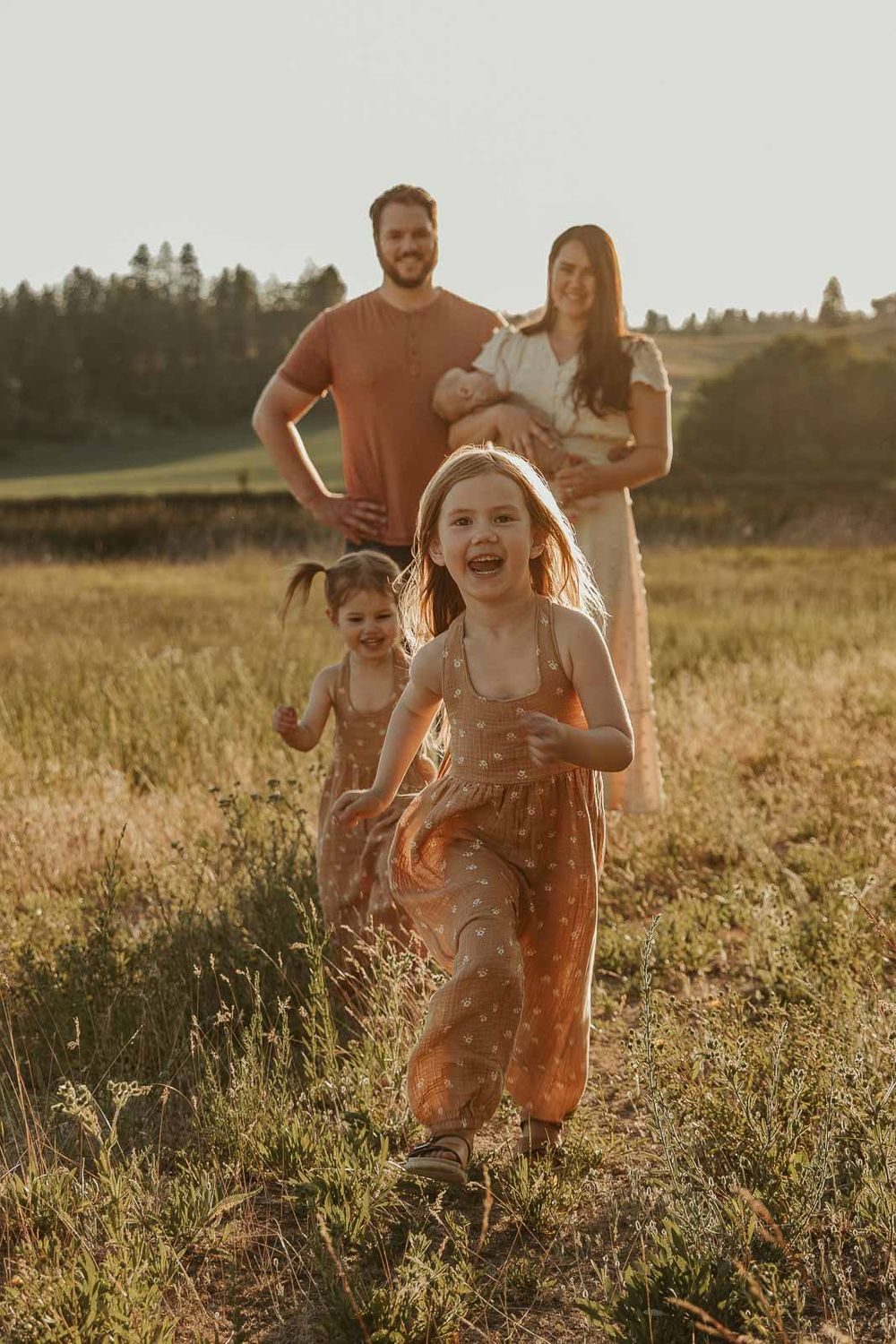 family of five in spokane two little girls running towards mom and dad all wearing earth tone outfits
