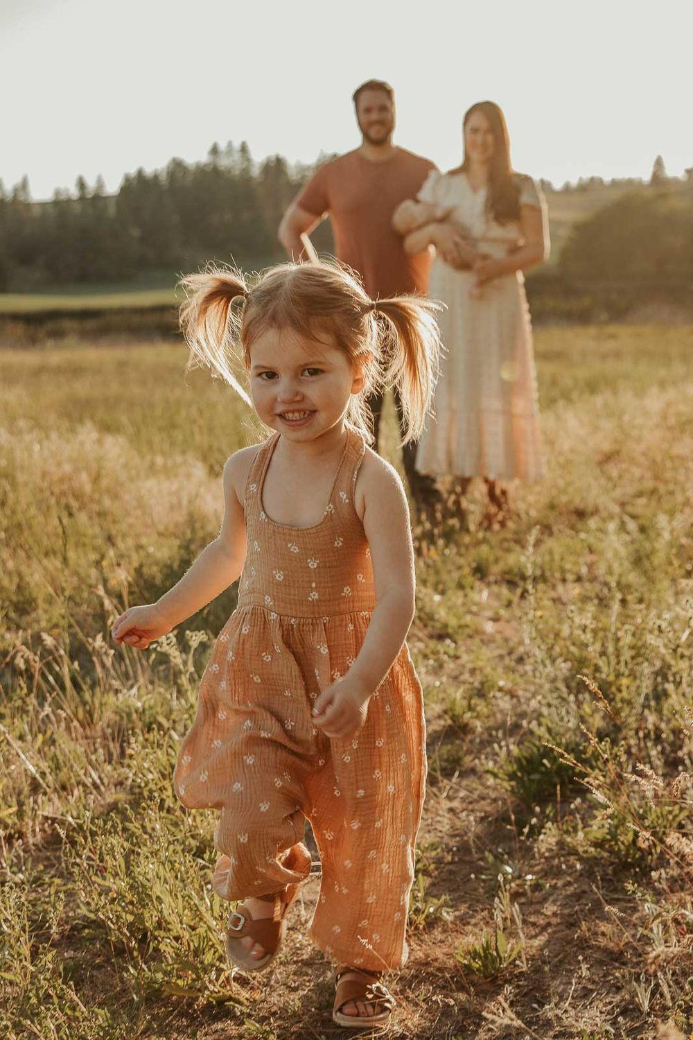 family of five in spokane little girl running towards mom and dad all wearing earth tone outfits