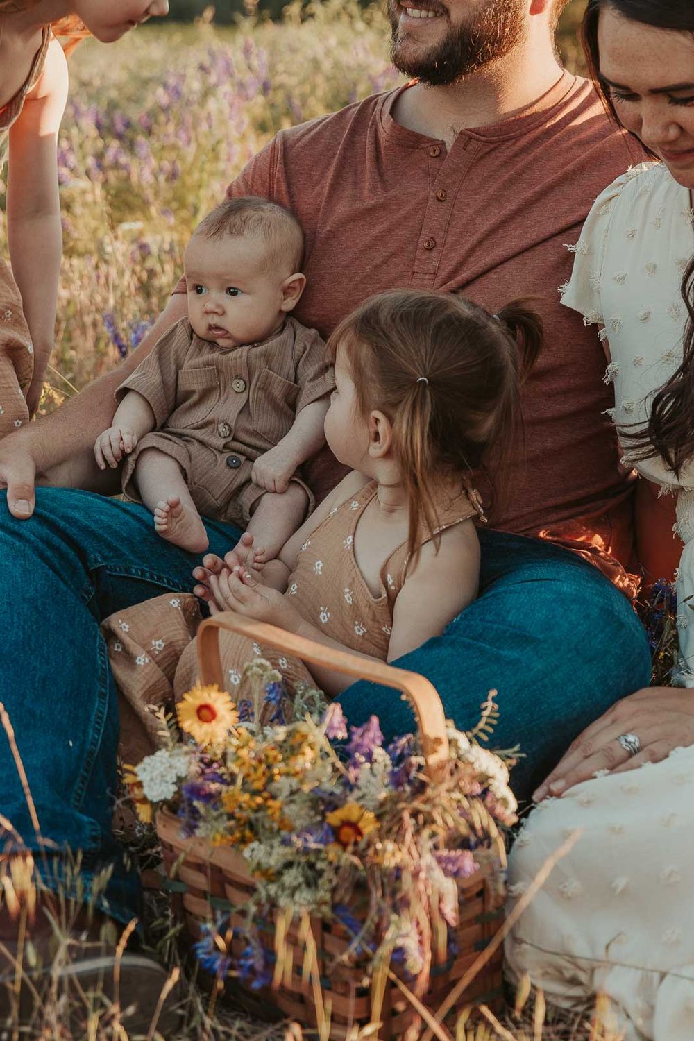 spokane family sitting in a flower field big sister is smiling at baby brother