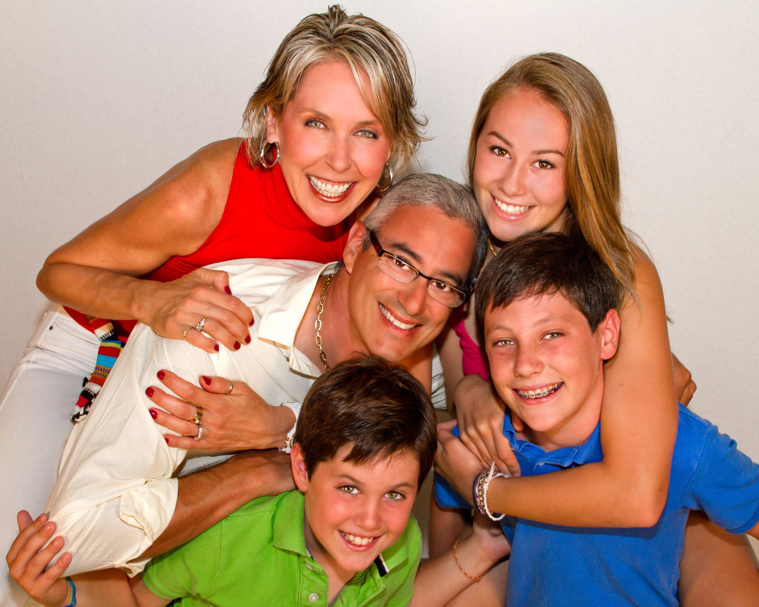 Happy family of five sharing a warm embrace, smiling together in a fun studio portrait session.