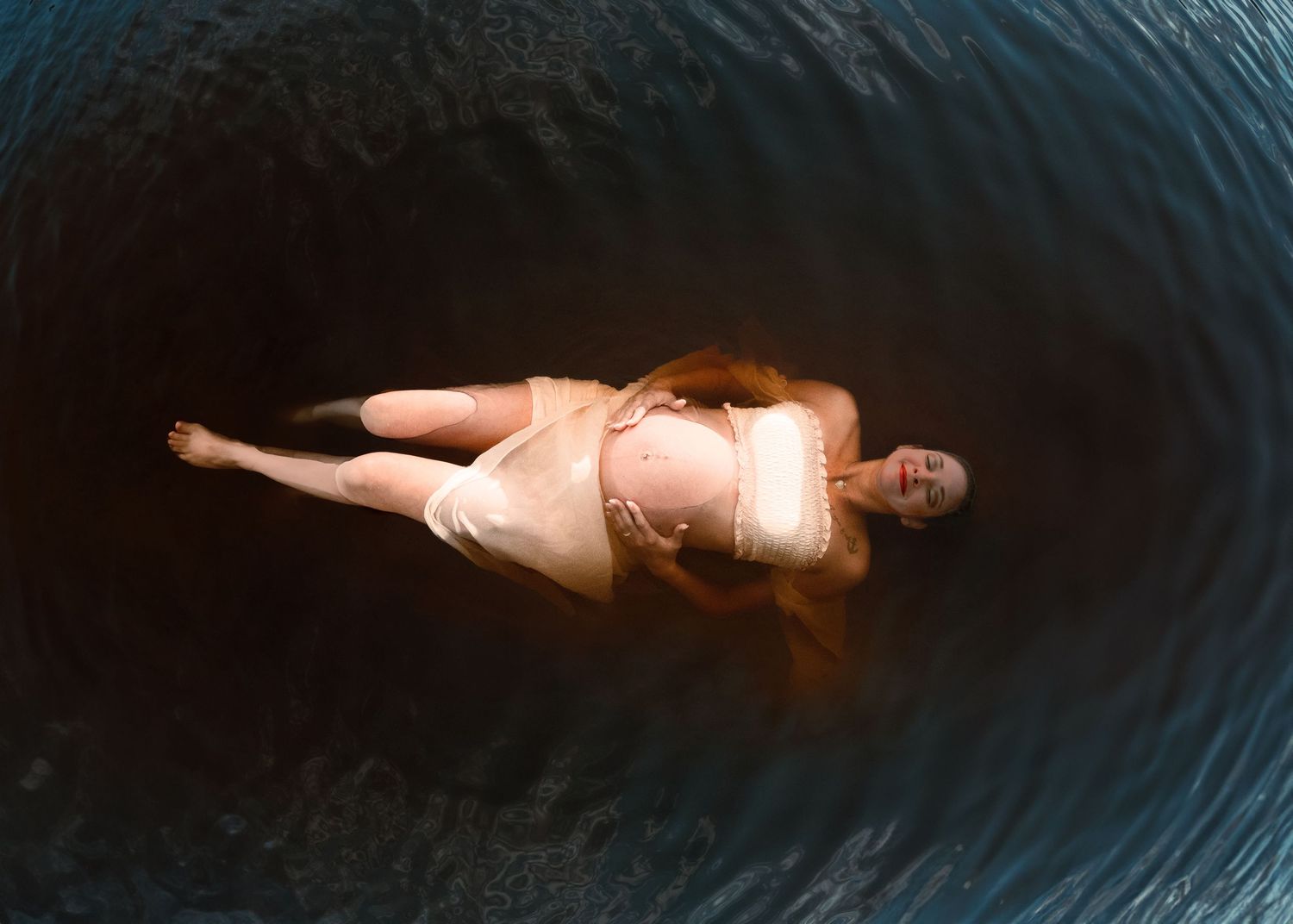 Young mom floating in Florida waters during her maternity photos. Cred: LexTakePix