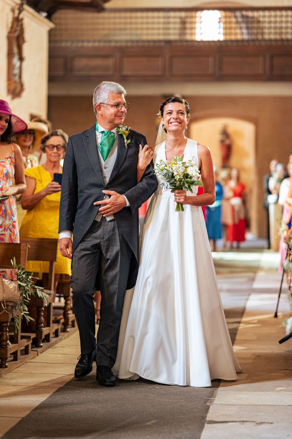 Traditional wedding procession down the church aisle with elegant white gown and formal attire.