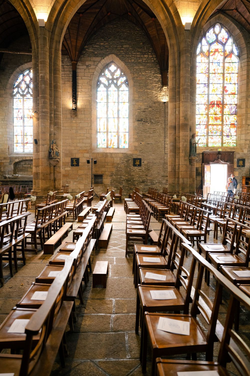 Ancient church interior with rows of wooden pews and stained glass windows illuminating the stone architecture.