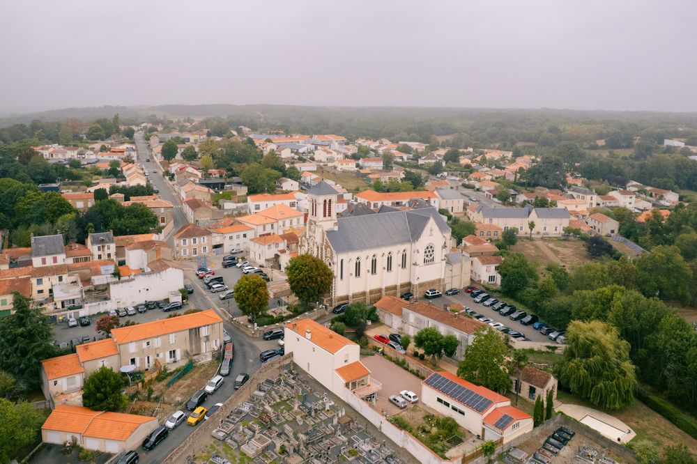 Aerial panoramic view of a coastal Portuguese town with traditional orange-tiled roofs and white buildings.