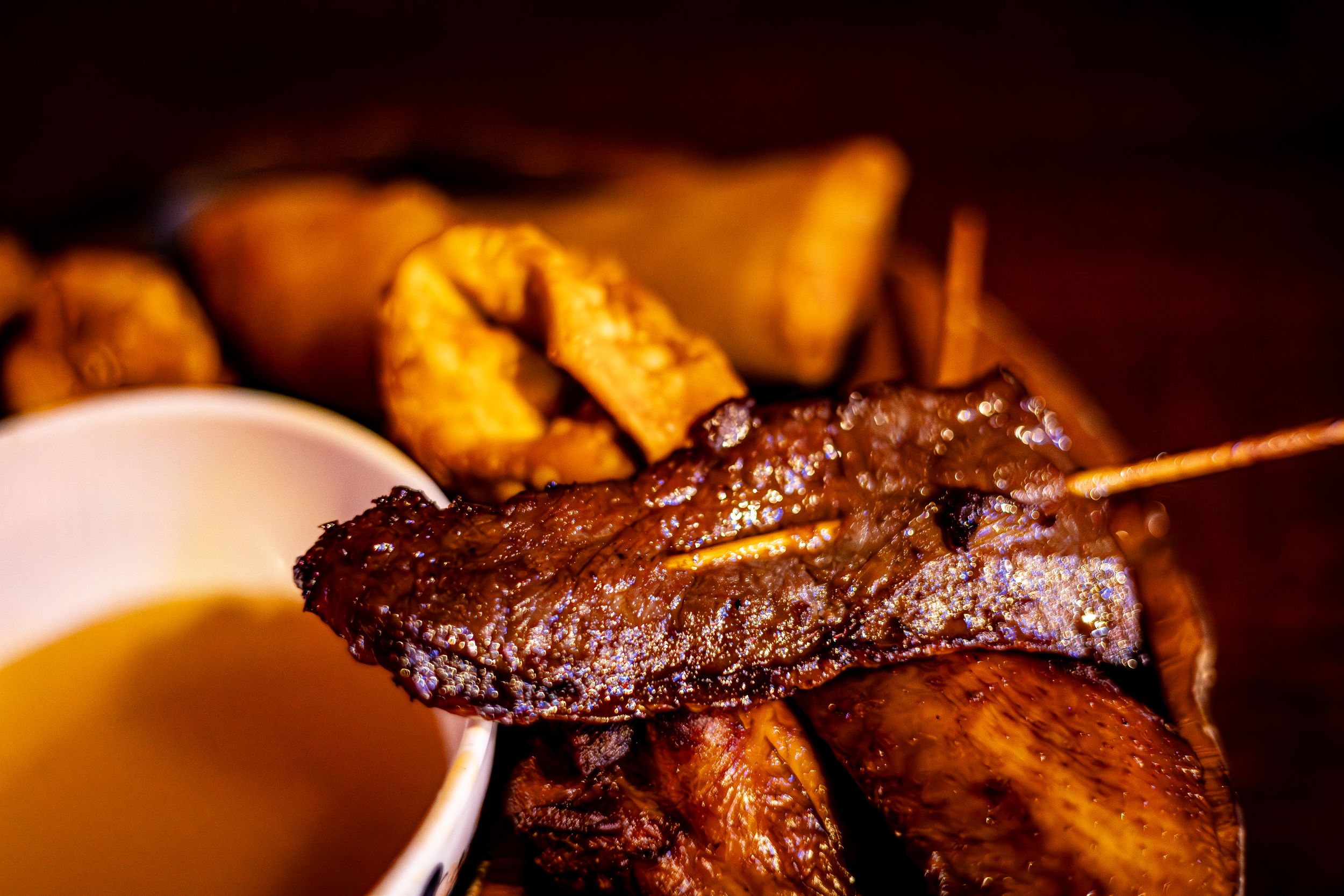 Grilled meat skewer with charred edges served alongside golden potatoes.