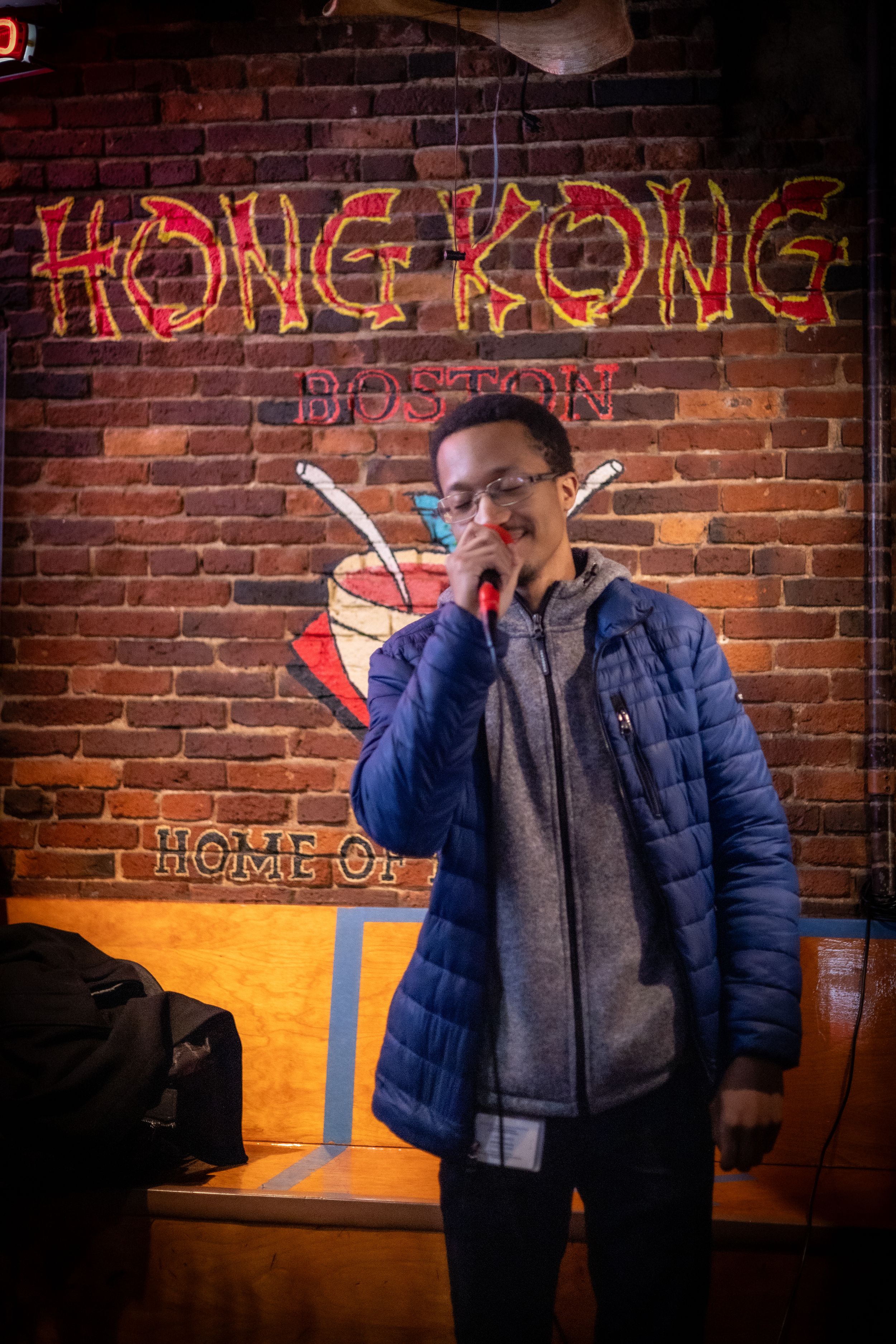 Red neon Hong Kong sign glows on brick wall in restaurant setting.