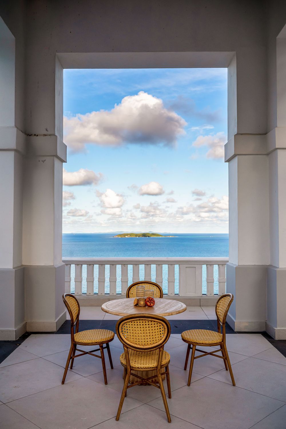 Oceanfront terrace seating area with cane chairs offering stunning views of the tropical coastline.
