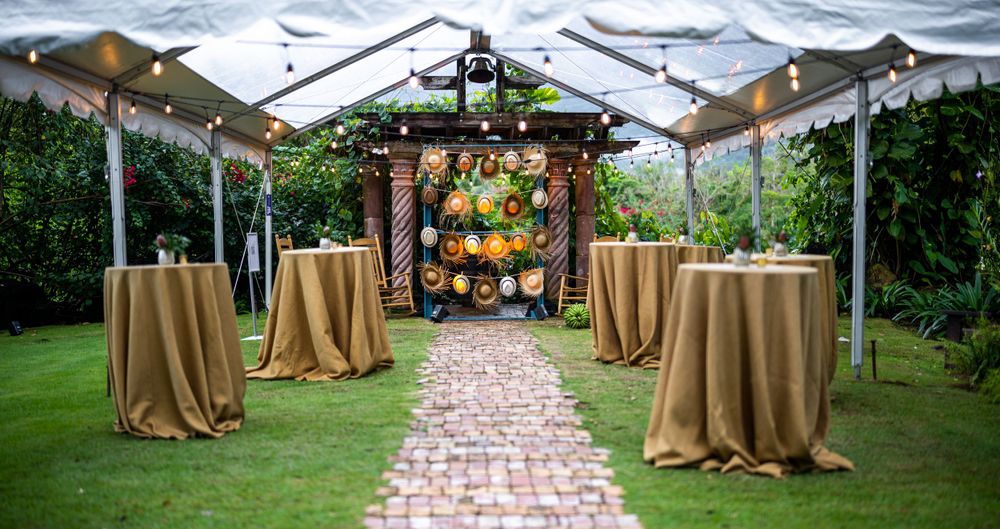 Outdoor wedding setup with champagne-colored tablecloths and rustic wooden archway.