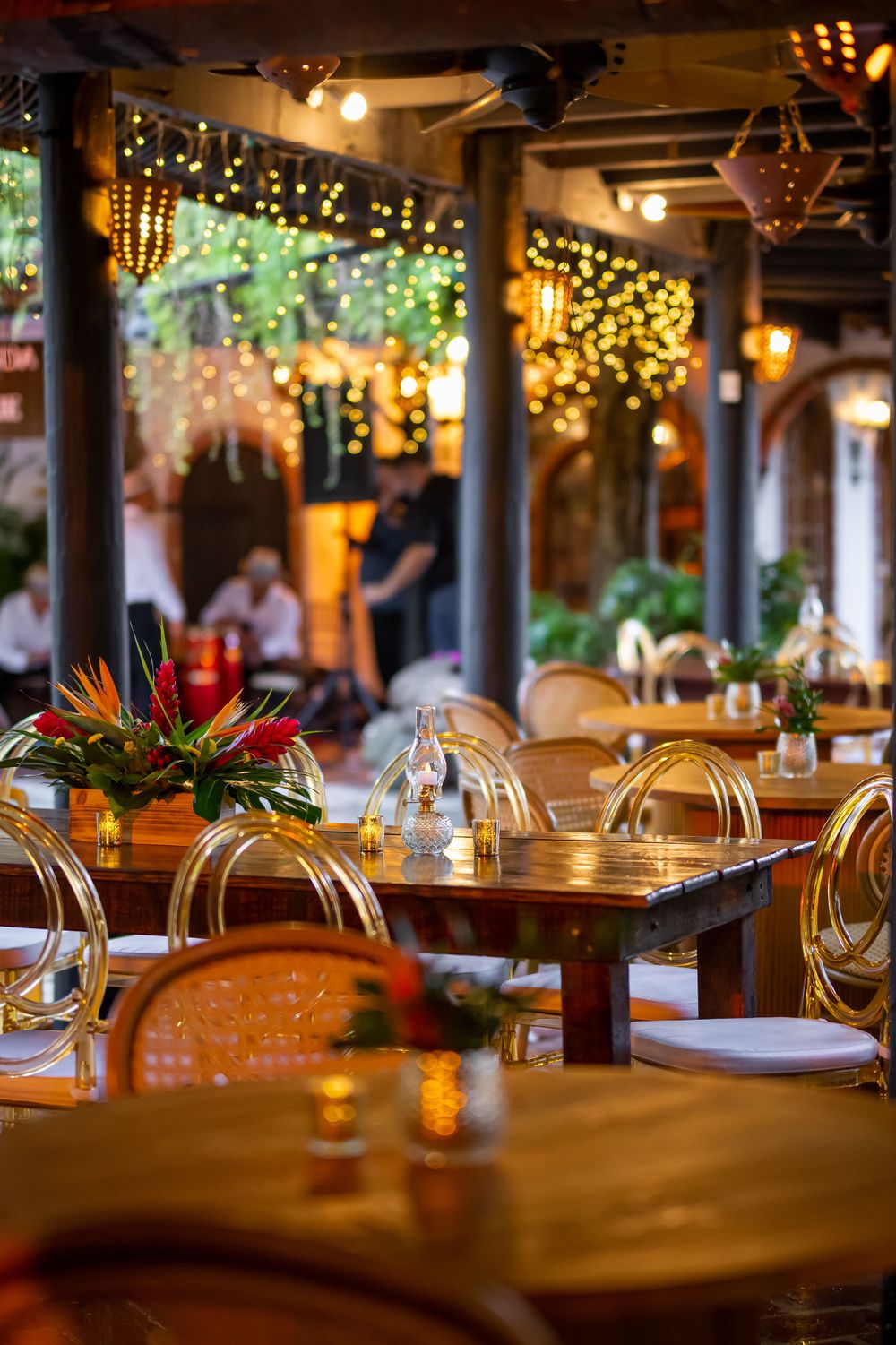 Restaurant dining area with warm ambient lighting and wooden tables with clear chairs.