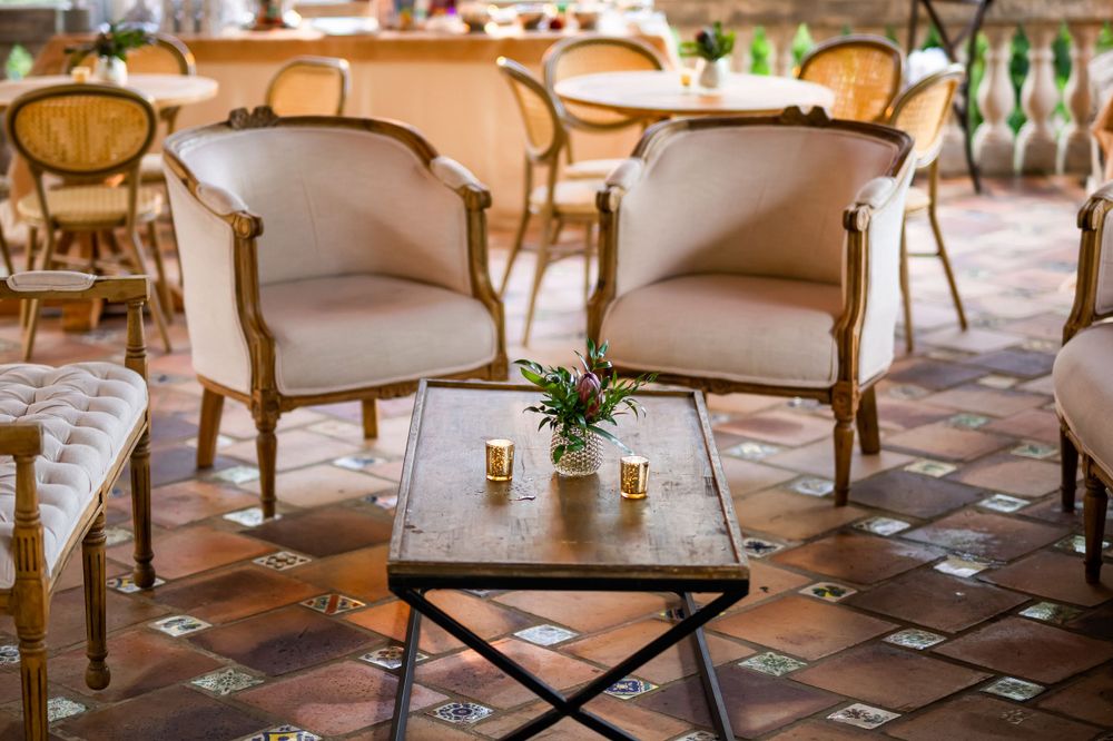 Elegant lounge area with cream upholstered chairs and dark wood coffee table on terracotta tiles.