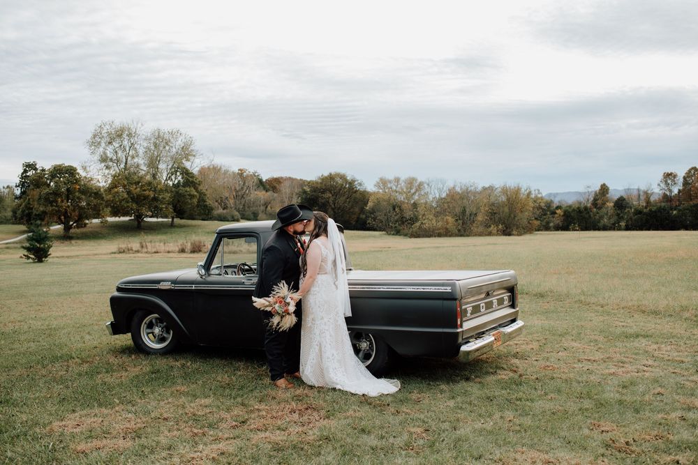 Couple celebrating western-themed wedding at rustic barn in Tennessee with vintage truck