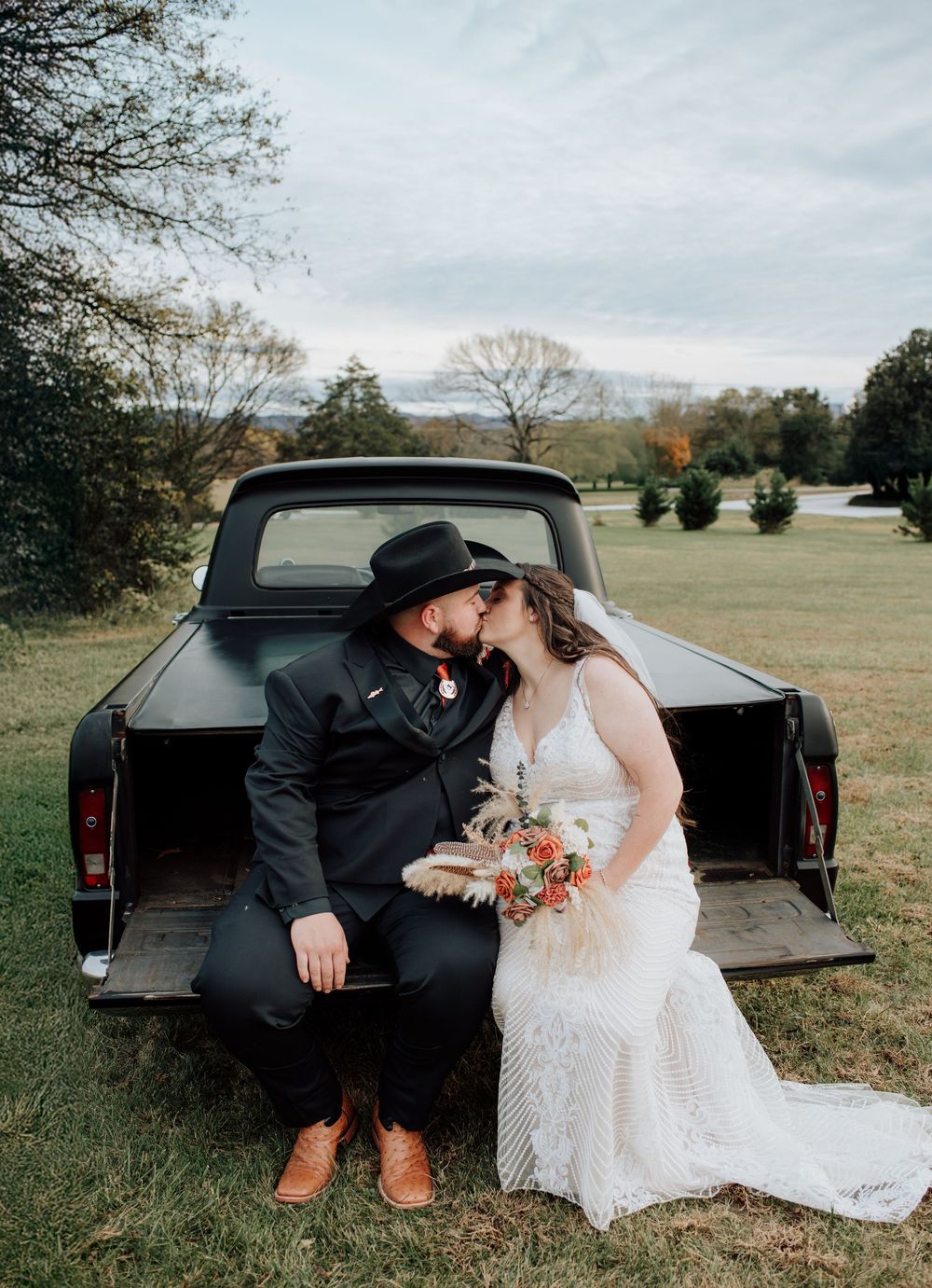 Couple celebrating western-themed wedding at rustic barn in Tennessee with vintage truck