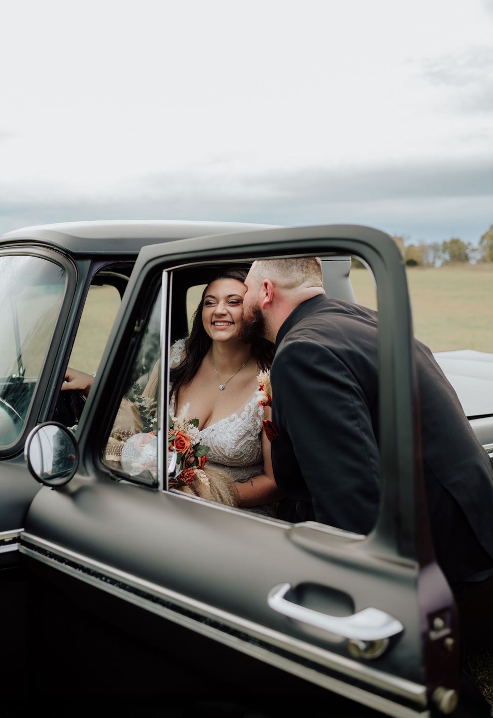 Couple celebrating western-themed wedding at rustic barn in Tennessee with vintage truck