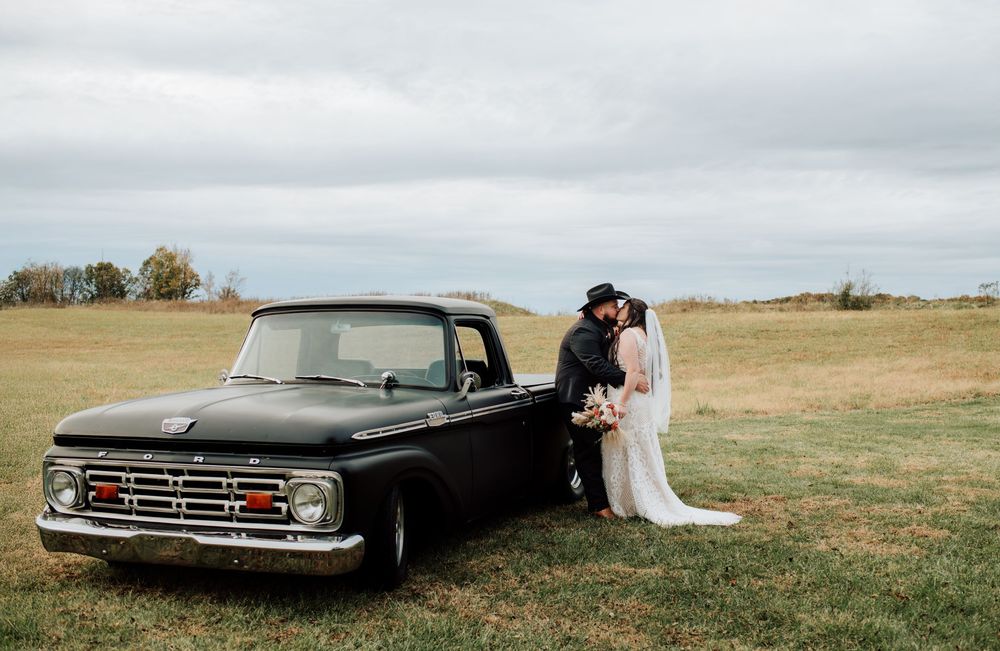Couple celebrating western-themed wedding at rustic barn in Tennessee with vintage truck