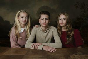 fine-art portret van 2 zussen en een broer zitten naast elkaar aan een tafel.