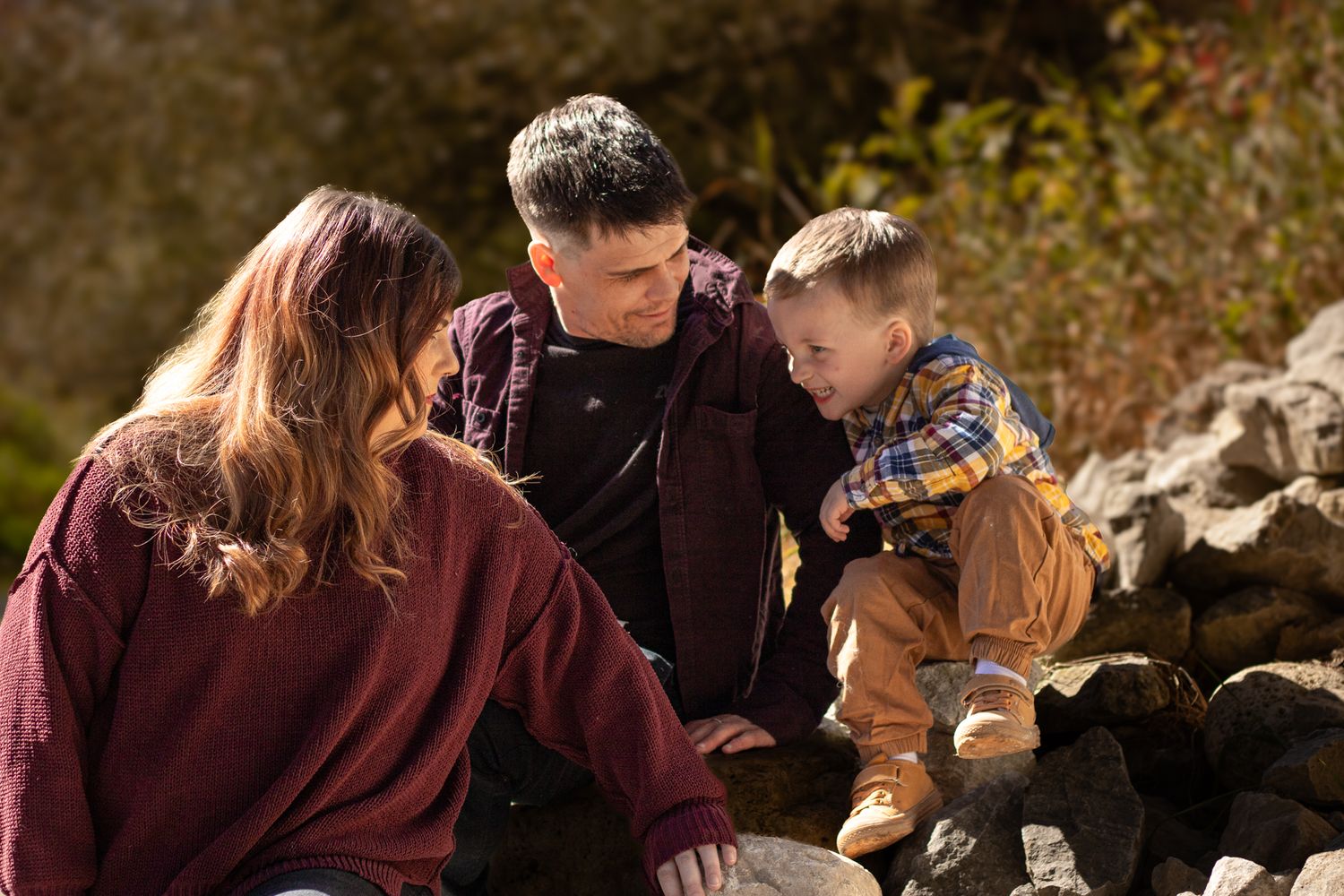 Family of three sitting on rocks in the sun