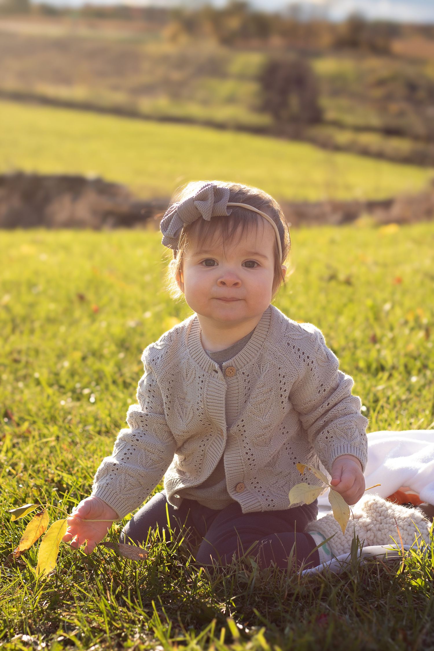 baby in a field with the sun glowing behind