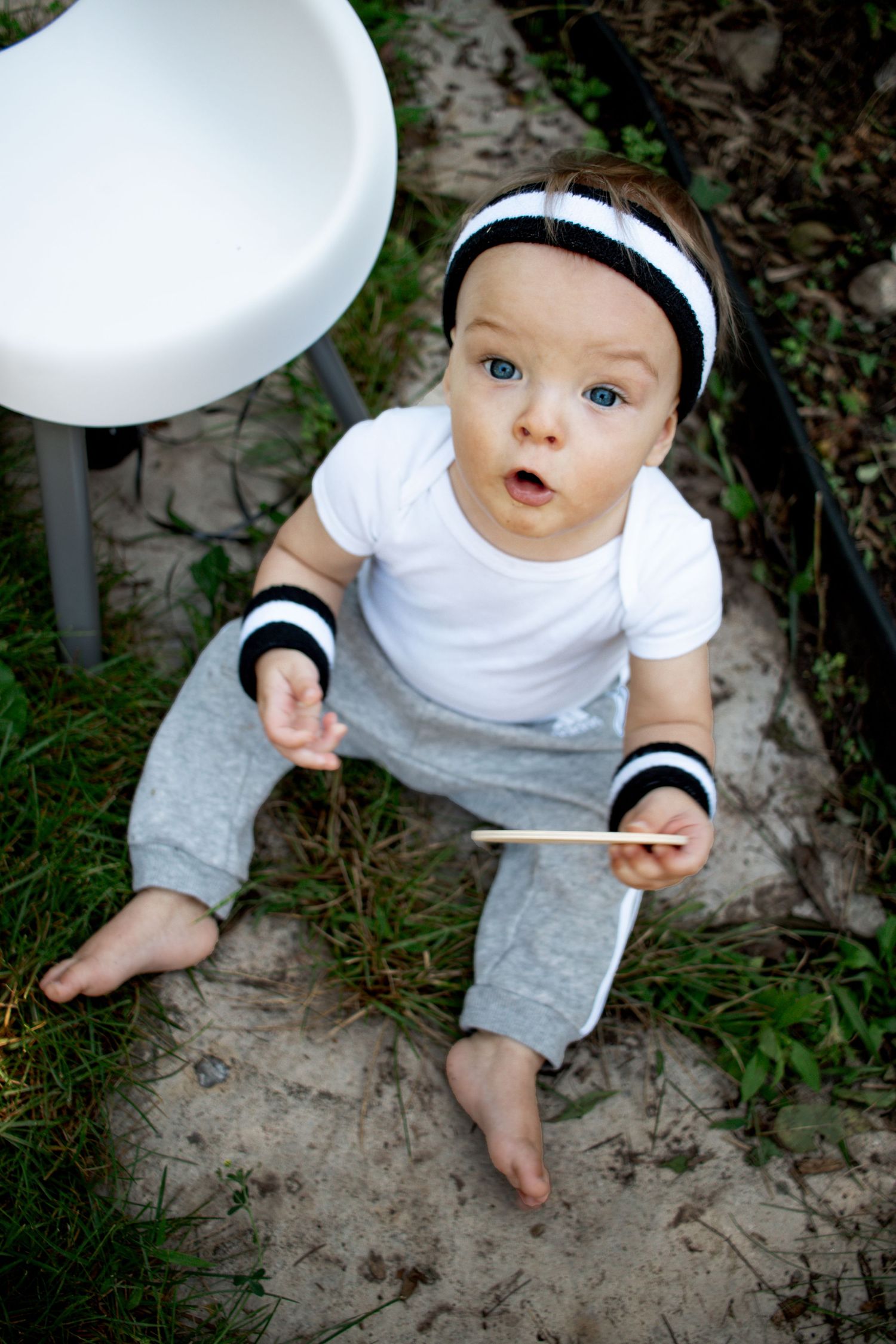 Baby sitting on patio stones looking up at the camera