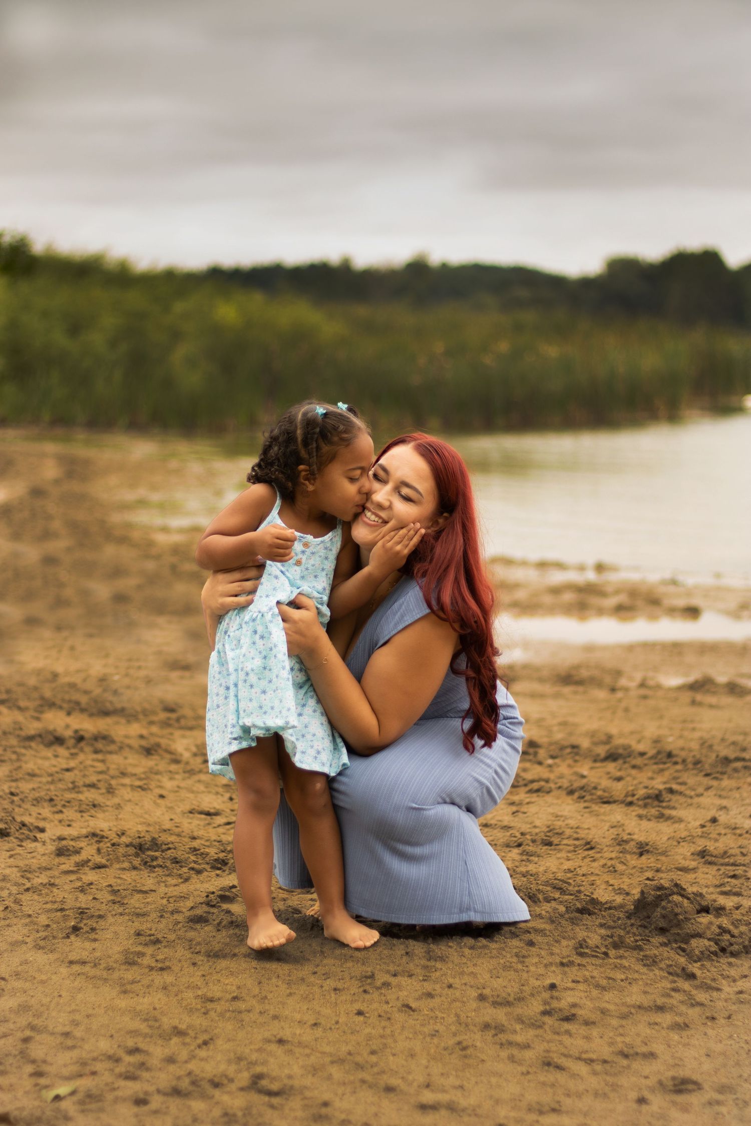 Mother and daughter on the beach, daughter kissing mom