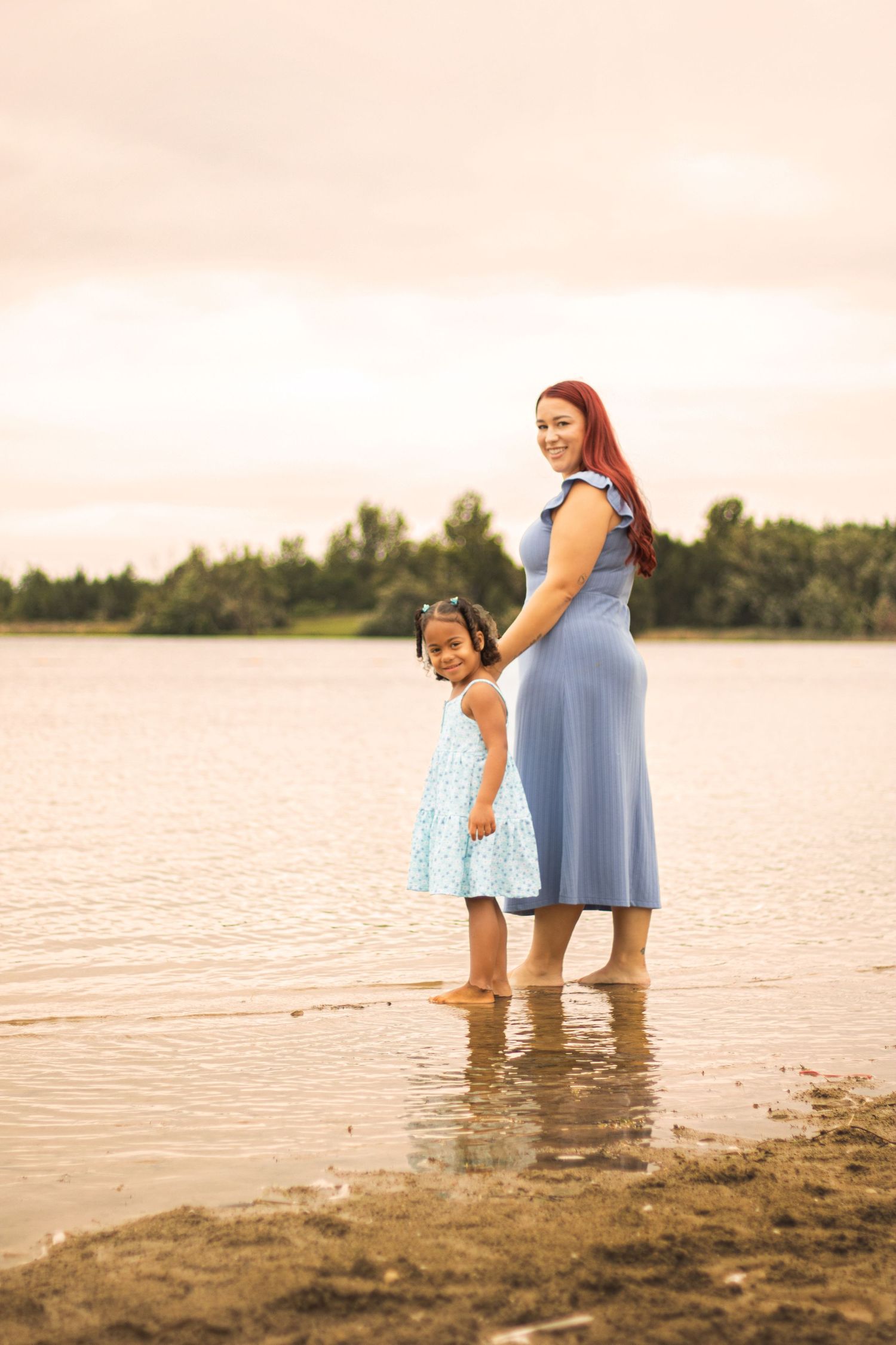 Mom and daughter walking in the lake looking back at the camera