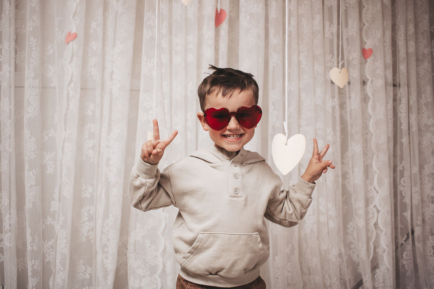 Preschooler in heart sunglasses throwing the peace sign