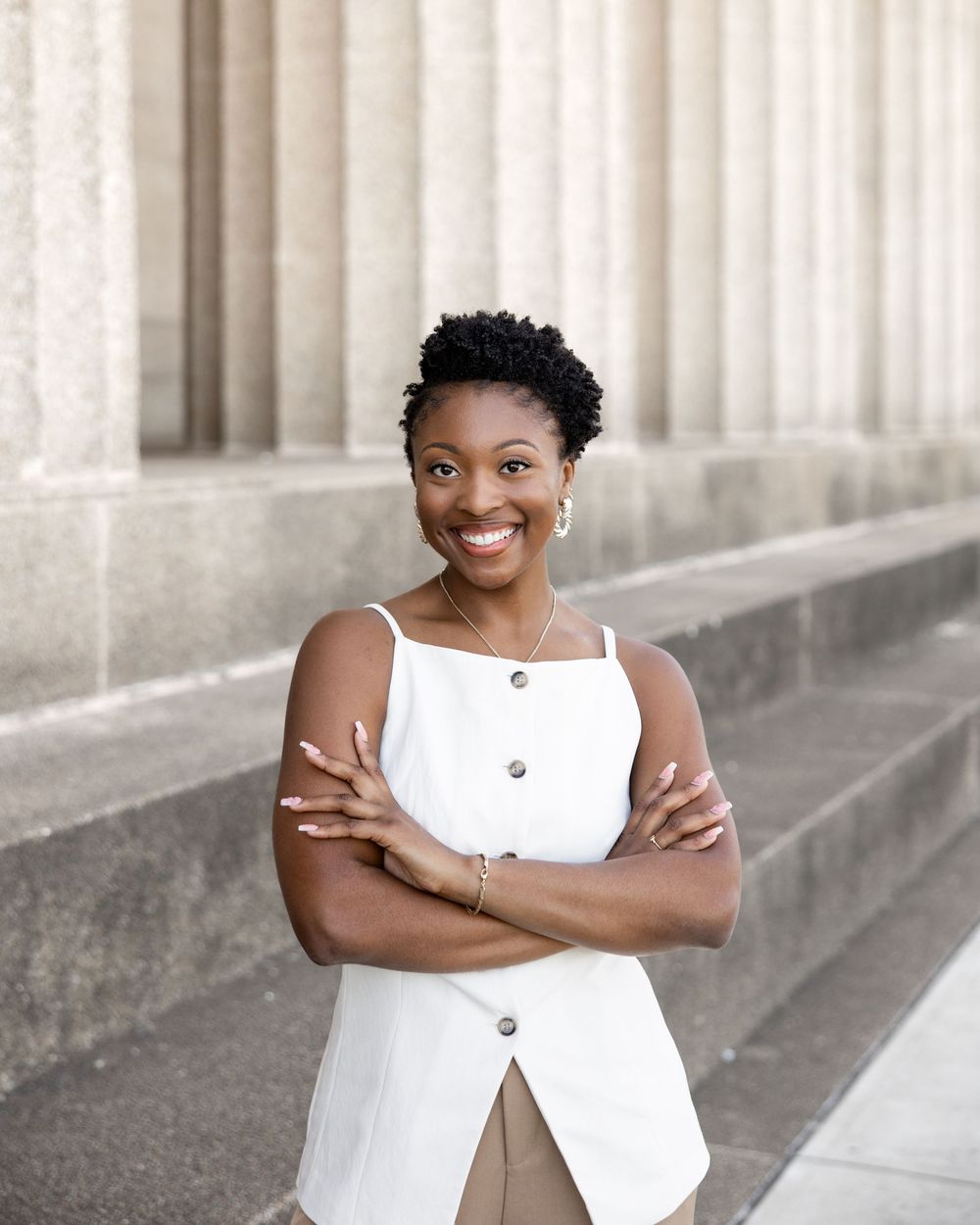 A series of five portrait photos showing someone in a white sleeveless top posing confidently against a stone column backdrop.