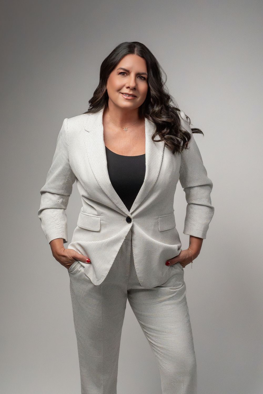Professional portrait of person in crisp white blazer and pants standing confidently.